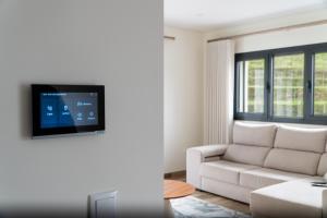 a living room with a white couch and a tv at Casa do Paçô - Cabeceiras de Basto in Cabeceiras de Basto