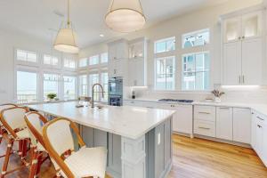 a kitchen with white cabinets and a large island with chairs at Palmilla Beach Sunrise Dreams in Port Aransas