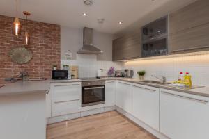 a kitchen with white cabinets and a brick wall at Lancaster City Apartment in Lancaster