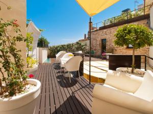 a balcony with white chairs and potted plants at Cas Ferrer Nou Hotelet in Alcudia