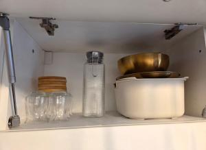 a kitchen shelf with glass jars and a bottle at Kucica Yuva in Vrnjačka Banja