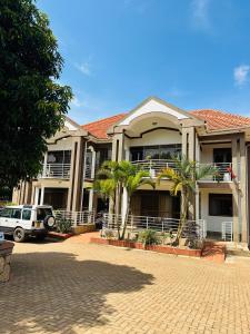 a large house with palm trees in front of it at Hidden beautiful Modern Apartment in Entebbe