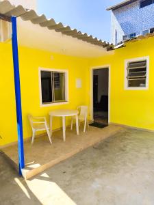 a yellow house with a table and chairs on a patio at Microcasa com ar em Resende in Resende