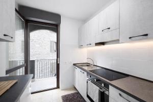 a kitchen with white cabinets and a large window at Bella Vita Stays Cozy in Sondrio +7 photos