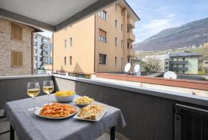 a table with two plates of food and glasses of wine at Bella Vita Stays Cozy in Sondrio