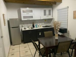 a kitchen with a table and a sink and a refrigerator at Cozy 2BR Cabin for 5 with Pool in Cabo Rojo