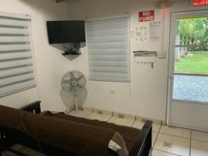 a living room with a couch and a fan at Cozy 2BR Cabin for 5 with Pool in Cabo Rojo