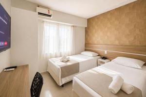 a hotel room with two beds and a tv at Assay Plaza Hotel in Hortolândia