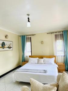 a bedroom with a large white bed with blue curtains at Hidden beautiful Modern Apartment in Entebbe