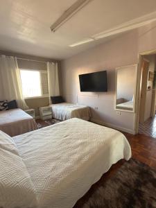 a hotel room with two beds and a flat screen tv at Sobrado versátil in Santo André