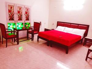 a bedroom with a red bed and a table and chairs at Hotel Sanskar in Pachmarhī