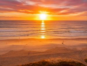 a sunset on a beach with the ocean at Absolute Beachfront Ocean Balcony Heated Pool in Gold Coast