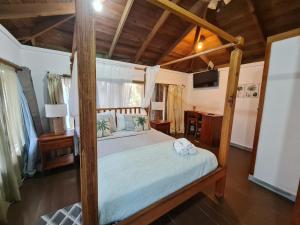 a bedroom with a canopy bed with a table and a desk at Las Palmas Beach Roatan in Dixon Cove
