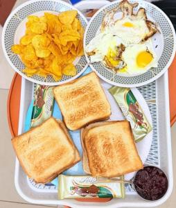 two plates of food with toast and eggs and chips at Coral Bay Suite Hotel in Khor Fakkan