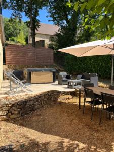 a patio with a table and an umbrella at Gîte - Le Petit Noyer in Le Bugue