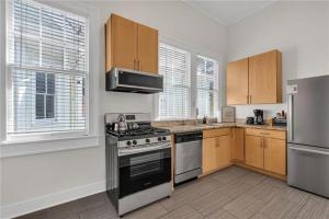 a kitchen with stainless steel appliances and wooden cabinets at Prytania Pearl - 3 Bedroom 2 Bathroom Home in New Orleans