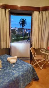 een slaapkamer met een bed en een raam met een palmboom bij Residência Aviz in Peniche