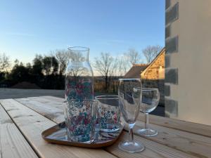 three wine glasses and a vase on a wooden table at Bleu horizon in Rosnoën