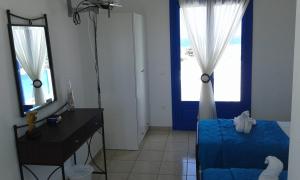 a room with a bed and a desk and two windows at Vigles in Adamantas