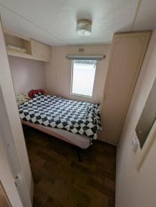 a small bedroom with a bed with a checkered blanket at Casa di Palli in Mariënberg