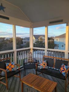 a screened in porch with benches and tables and windows at Steps to Beach Pool Game Room Aug Weeks Open in Corolla