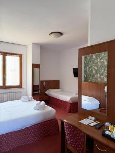 a hotel room with two beds and a desk and a mirror at Fell Hotel in Susa