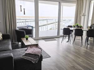 a living room with a couch and a table with chairs at Exklusive Meerblickwohnung in 1 Reihe in Wendtorf