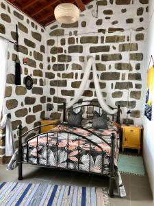a bedroom with a stone wall with a bed at Casa Auri in Faial da Terra