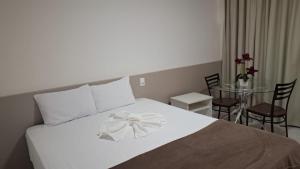 a bedroom with a white bed with a bow on it at Augustos Hotel in Santo Antônio de Jesus