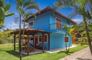 a blue house with a gazebo and palm trees at Capoeira Village in Porto Seguro