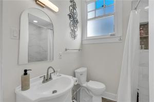 a white bathroom with a sink and a toilet at Prytania Pearl - 3 Bedroom 2 Bathroom Home in New Orleans +10 photos