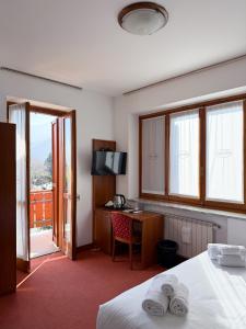 a hotel room with a bed and a desk and window at Fell Hotel in Susa