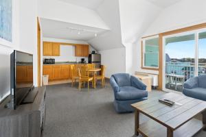 a living room with a tv and a kitchen at The Ocracoke Harbor Inn in Ocracoke