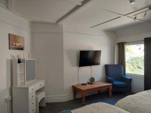 a bedroom with a bed and a tv and a chair at Royal Oak Rooms in Exeter