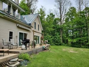 a house with a deck and a grill on a yard at Vermont Escape, Too in Warren
