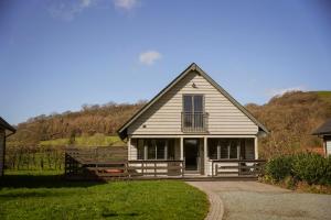 a small white house with a porch on a hill at Maple Lodge in Knighton