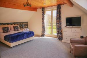 a bedroom with a bed and a tv and a window at Maple Lodge in Knighton
