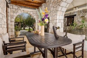 an outdoor dining room with a wooden table and chairs at Grantzaos Villas in Laganas
