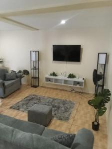 a living room with a couch and a flat screen tv at The Cupid Chalet Suite in Kingstown