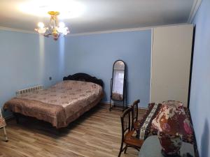 a bedroom with a bed and a chair and a mirror at Rest House in Quba