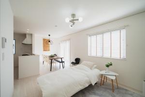 a white bedroom with a bed and a table at Guesthouse tontonmie in Gimbaru