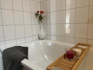 a bath tub with a vase of flowers and a candle at Hannas Place in Garding +19 photos