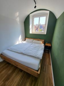 a bed in a room with a green wall and a window at Amtsstube1892 - Übernachten im alten Gefängnis in Überlingen