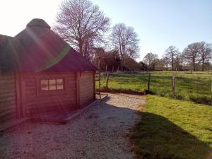 a small red building in a field with a fence at kota en Normandie in Couvains +1 photo