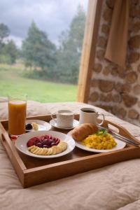 a tray with two plates of breakfast food and a drink at El Tiklan Glamping in Chucchilán