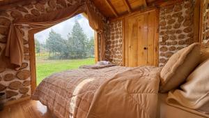 a bedroom with a bed and a large window at El Tiklan Glamping in Chucchilán