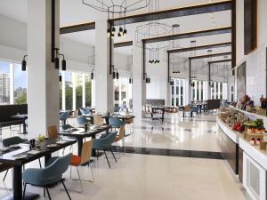 a restaurant with tables and chairs and windows at Novotel Kochi Infopark in Cochin