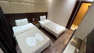 a small room with two beds with white sheets at Grand Elite Hotel in Cairo