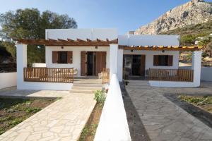 a white house with a mountain in the background at Villa Yvon Telendos - Villa # 1 in Telendos