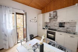 a kitchen with white cabinets and a table and a sink at Mediterranea Apartment in Agrigento